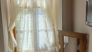A room with a window, a wooden dresser, and a mirror.