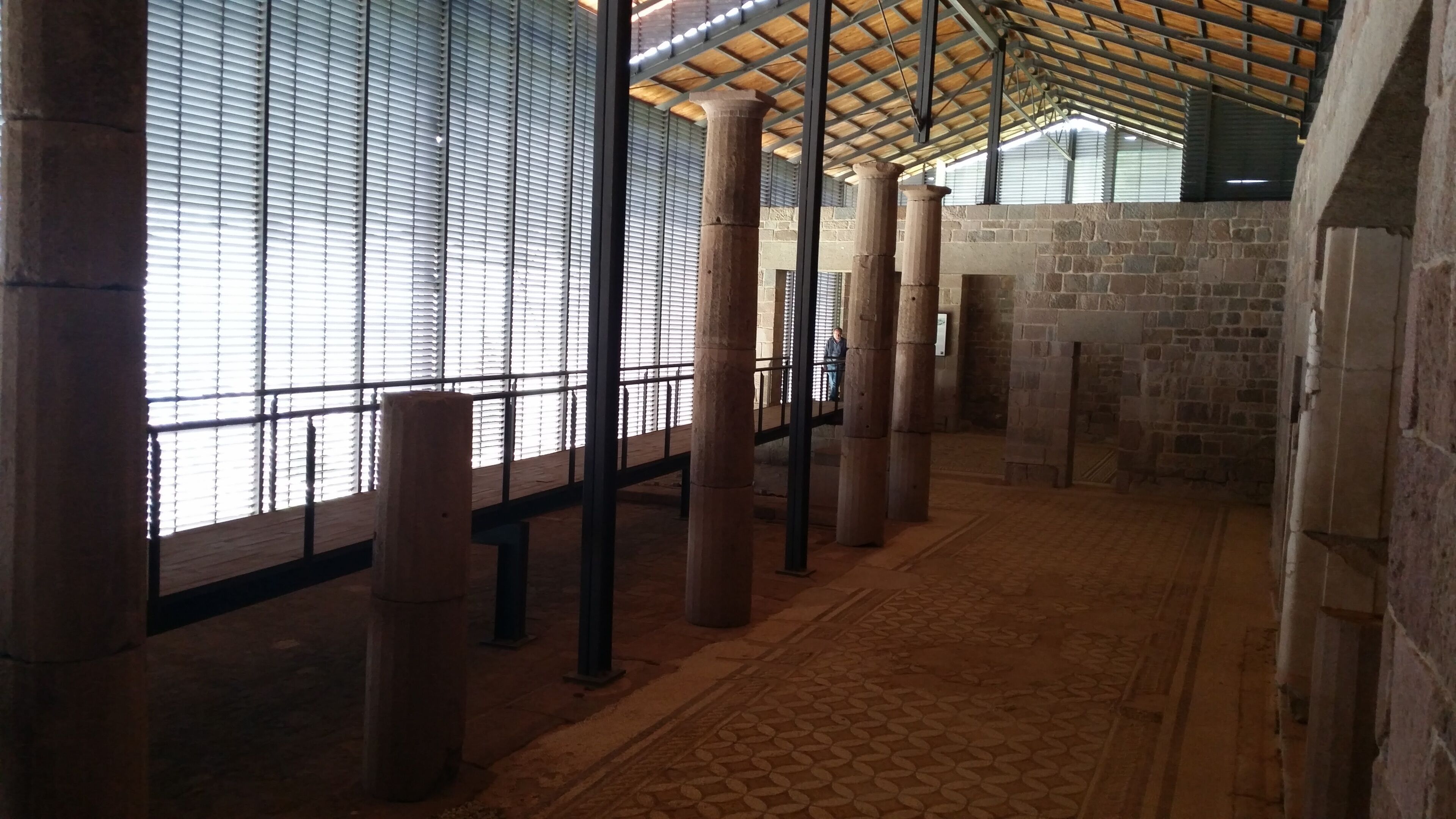 A room with large windows, stone pillars, and a patterned floor.