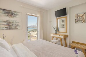 A bedroom with a bed, a desk, a chair, a television, and a painting.