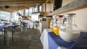 Un espace repas avec des tables et des chaises, un comptoir équipé d’appareils de cuisine et un plafond orné de poutres en bois.