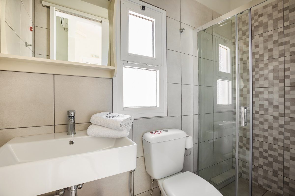 Un baño con lavamanos, inodoro y cabina de ducha de vidrio.