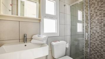 Un baño con lavamanos, inodoro y cabina de ducha de vidrio.