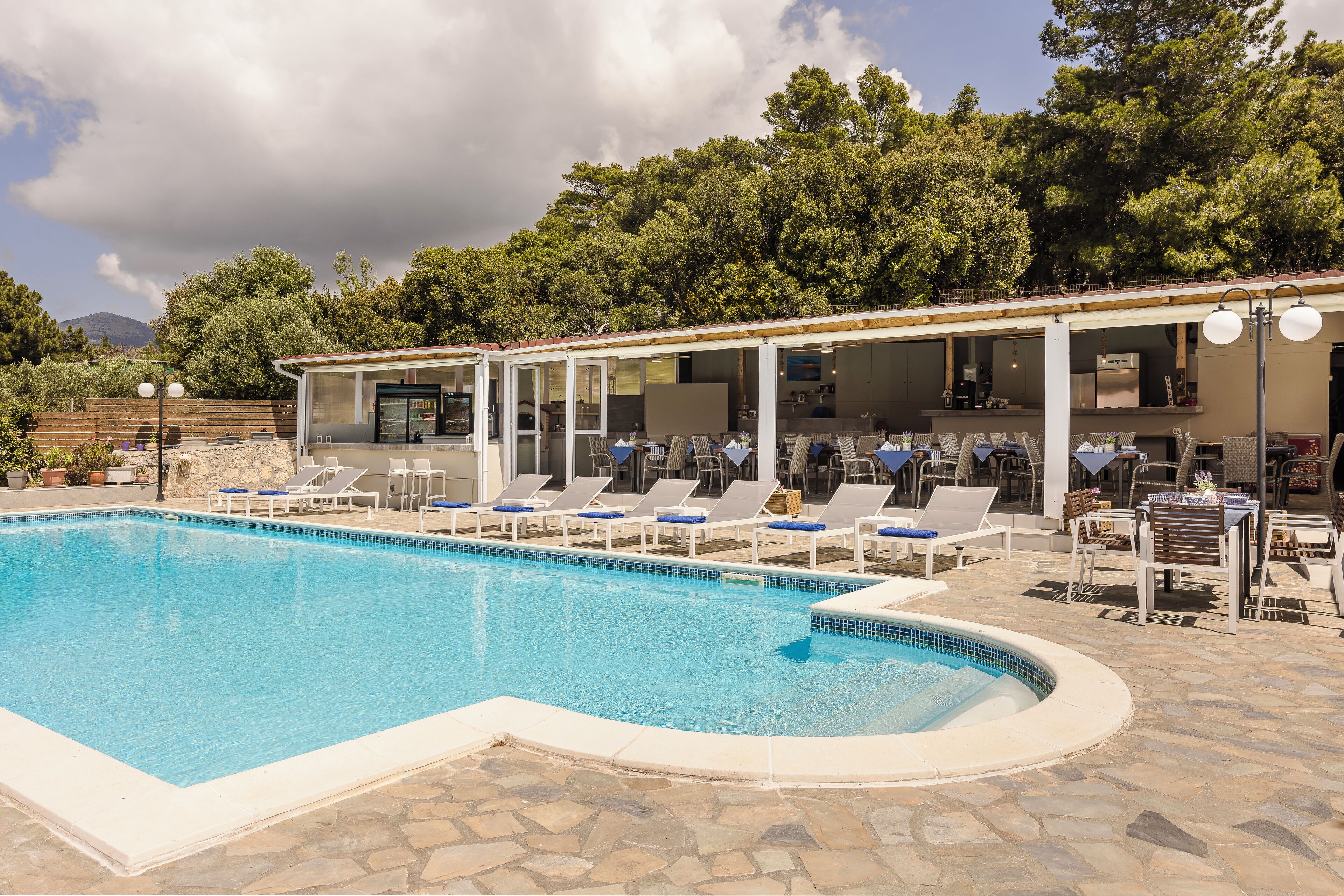 A swimming pool with lounge chairs and a covered seating area.