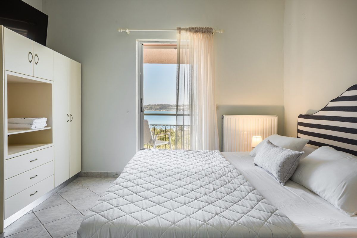 A bedroom with a bed, a wardrobe, a window with a view, and a bedside lamp.