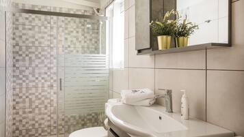 A bathroom with a glass shower enclosure, a white sink, and a mirror above it.