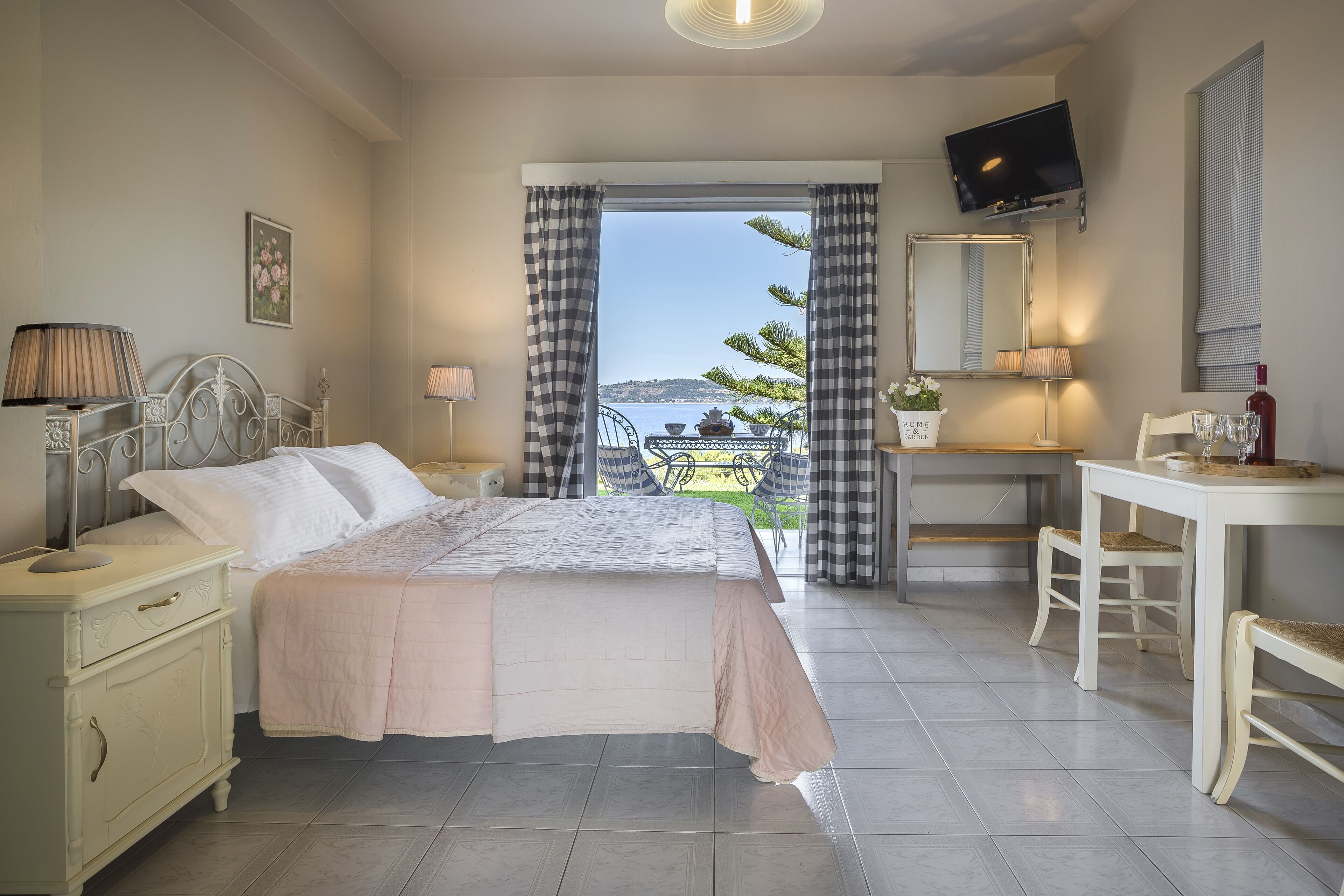 A bedroom with a bed, bedside table, lamp, and a view of the sea.