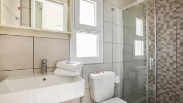 A bathroom with a white sink, a toilet, and a glass shower enclosure.