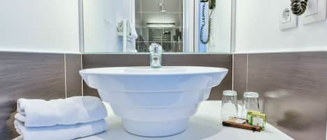 Un baño con un lavamanos grande de color blanco, un espejo y un perchero para toallas.