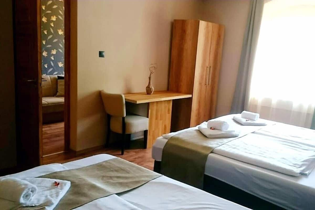 Ein Hotelzimmer mit zwei Betten, einem Schreibtisch und einem Kleiderschrank.