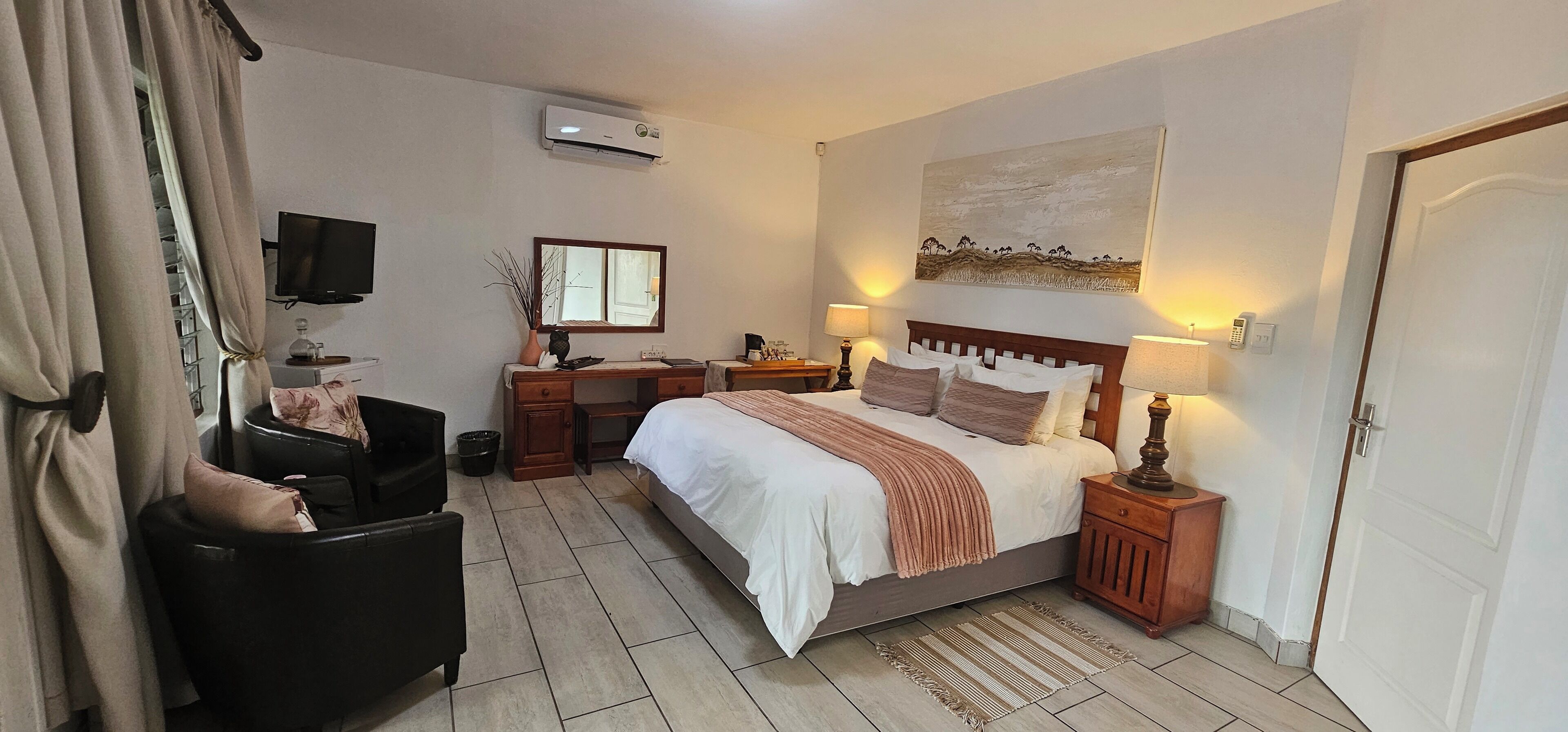 A hotel room with a bed, bedside tables, a TV, a desk, and a chair.