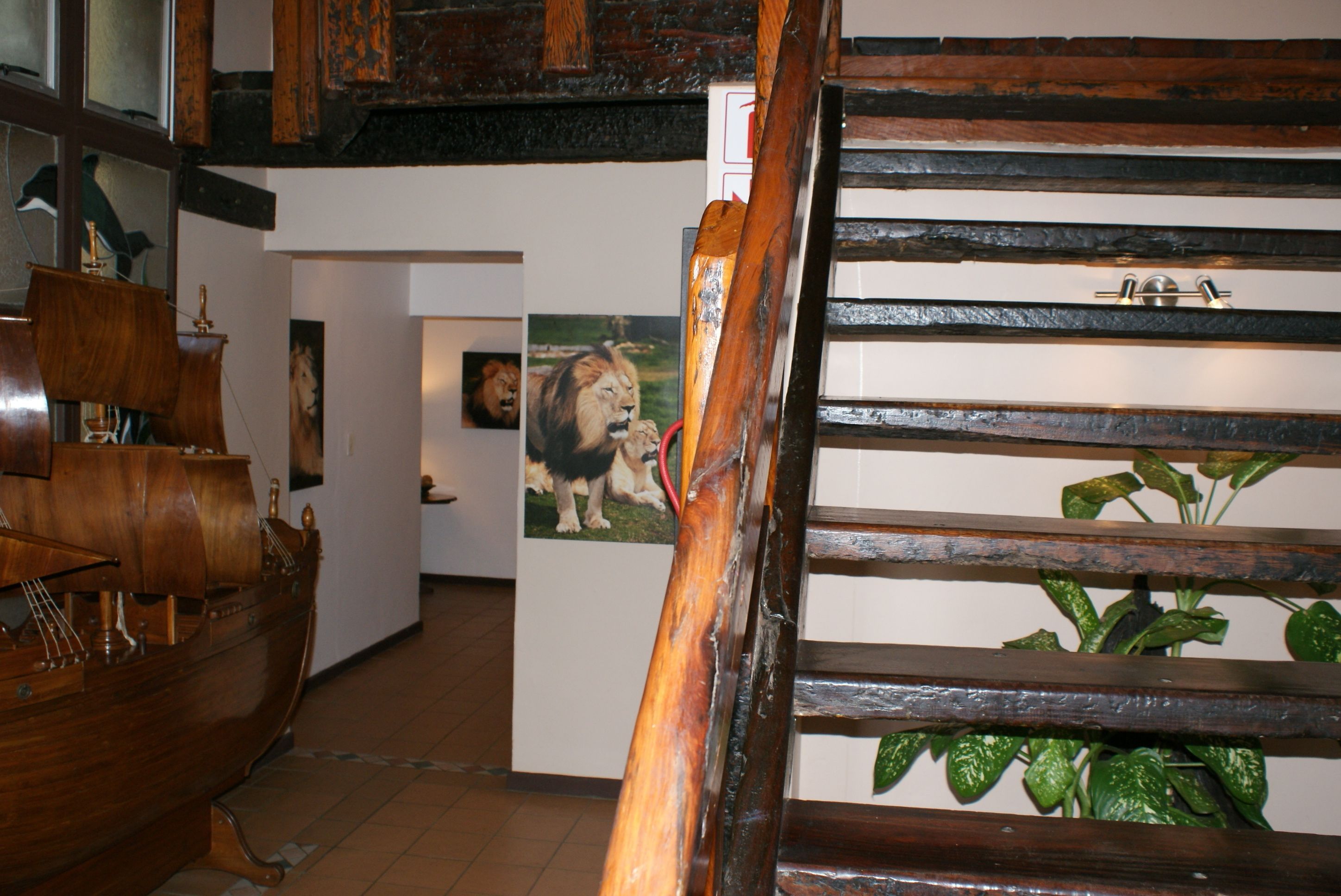 A wooden staircase with a ship model and a lion painting in the background.