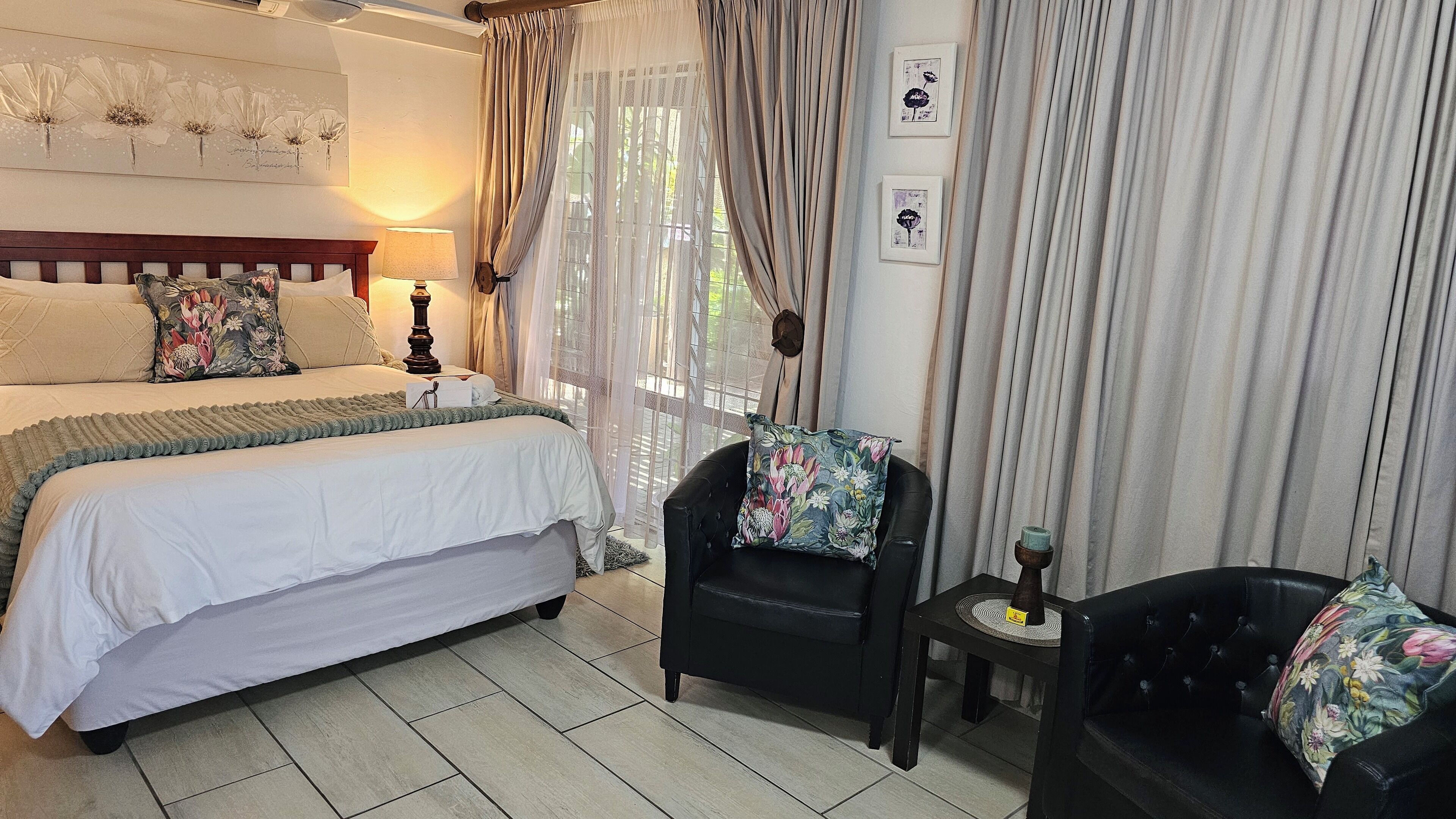 A bedroom with a double bed, a chair, a small table, and curtains.