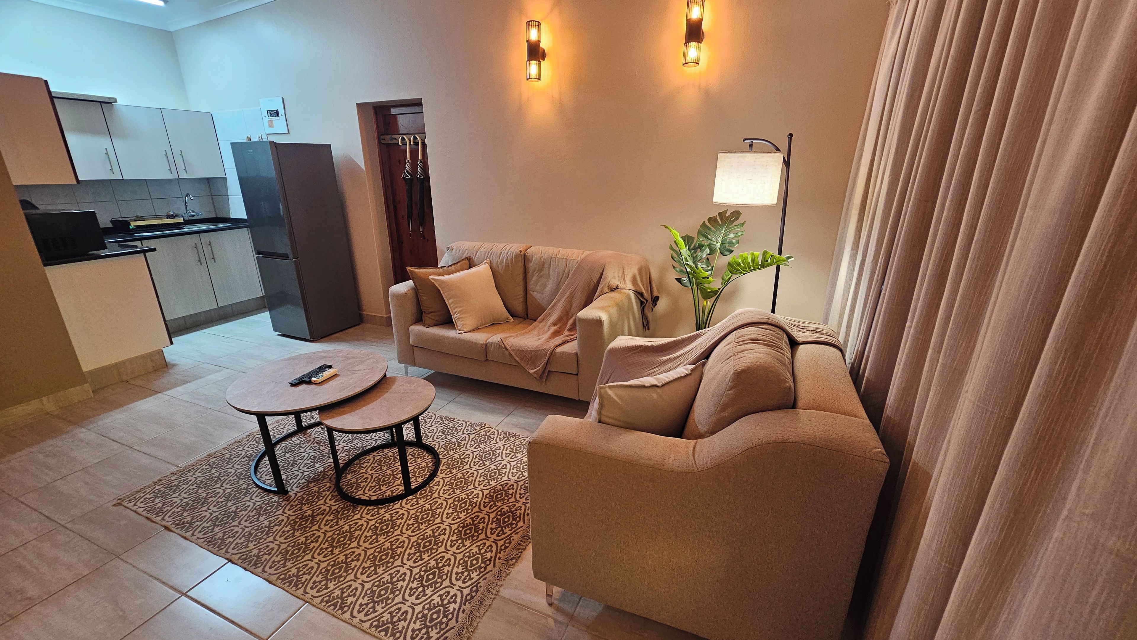 A living room with a sofa, two small tables, a plant, and a lamp.