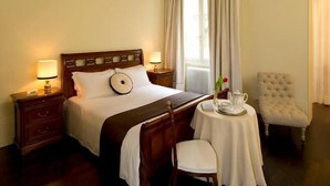 A hotel room with a large bed, a wooden nightstand, a round table with a tray, a chair, and a classic chandelier. - 1865 Residenza D'epoca (Florence)
