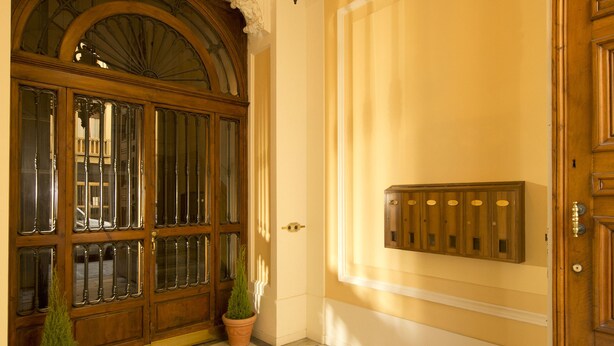 A hallway with a large wooden door, a decorative ceiling light, and a patterned floor. - 1865 Residenza D'epoca (Florence)