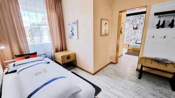 A hotel room with a bed, a small wooden nightstand, a whiteboard, and a coat rack.