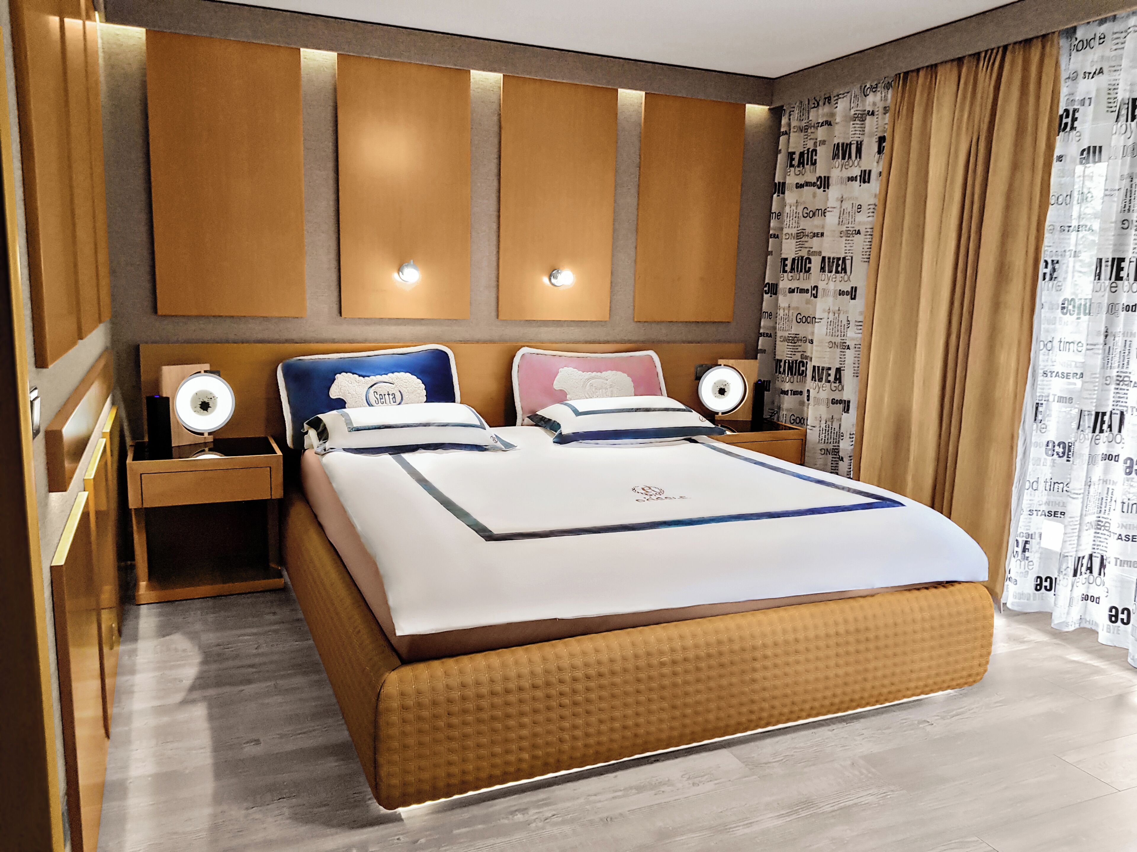Habitación de hotel con una cama grande, dos mesitas de noche y un cabecero con iluminación integrada.