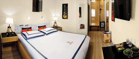 Habitación de hotel con una cama grande, mesitas de noche, televisión y un baño visible a través de una puerta abierta.