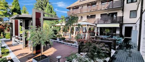A courtyard with outdoor seating, a pergola, and a pool area.