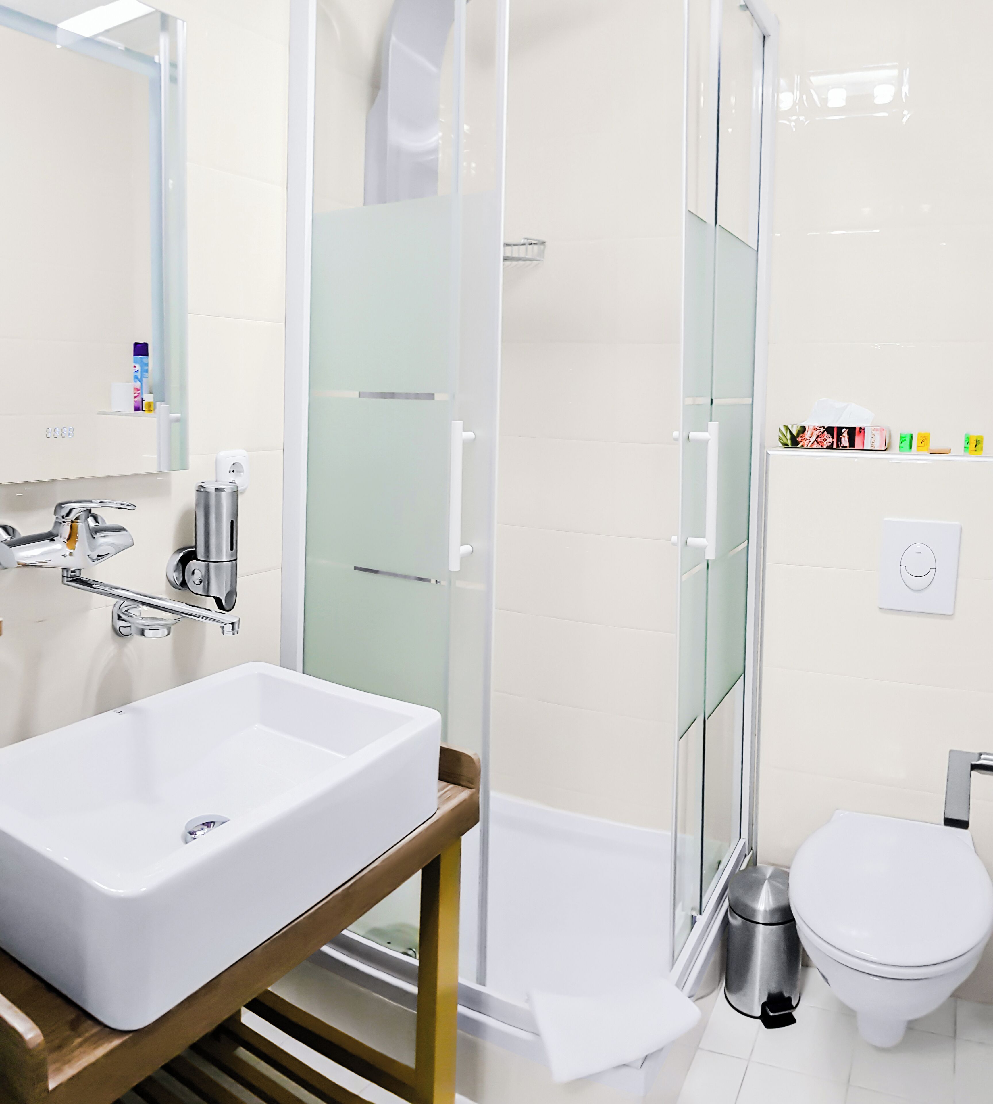 A modern bathroom with a large white sink, a glass shower enclosure, and a toilet.