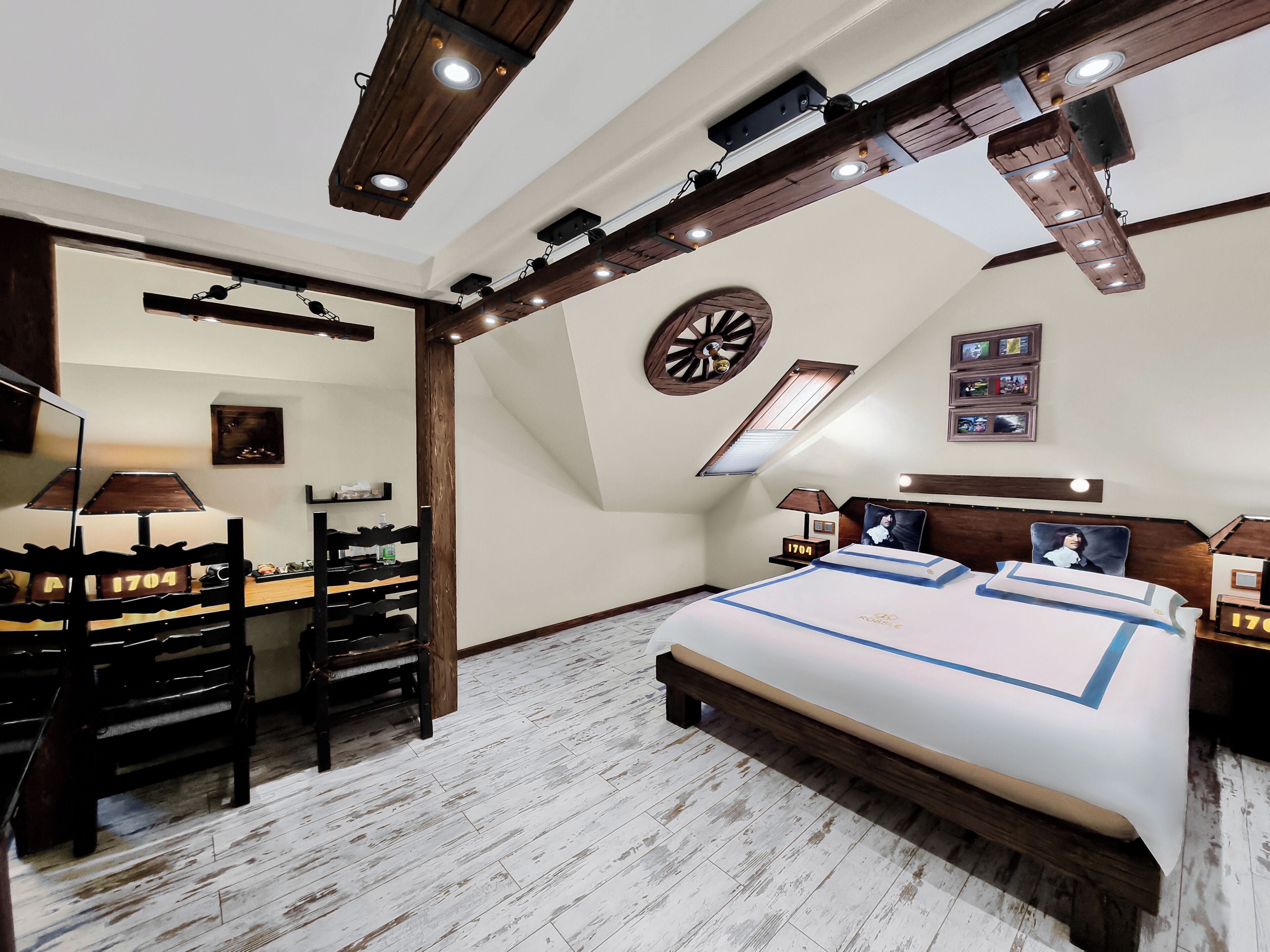 Une chambre avec un grand lit, un bureau et une chaise. Il y a une horloge au mur et une fenêtre donnant sur le ciel.