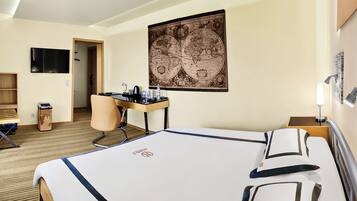 Quarto de hotel com cama, escrivaninha, cadeira e um grande mapa na parede.