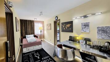 A hotel room with a bed, a desk, a chair, a map of the world, and a globe.
