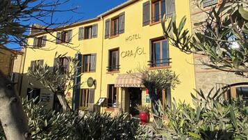 A yellow building with 'HOTEL' and 'RESTAURANT' signage, featuring a stone facade and multiple windows.