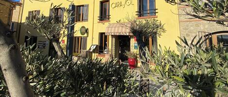 A yellow building with 'HOTEL' and 'RESTAURANT' signage, featuring a stone facade and multiple windows.