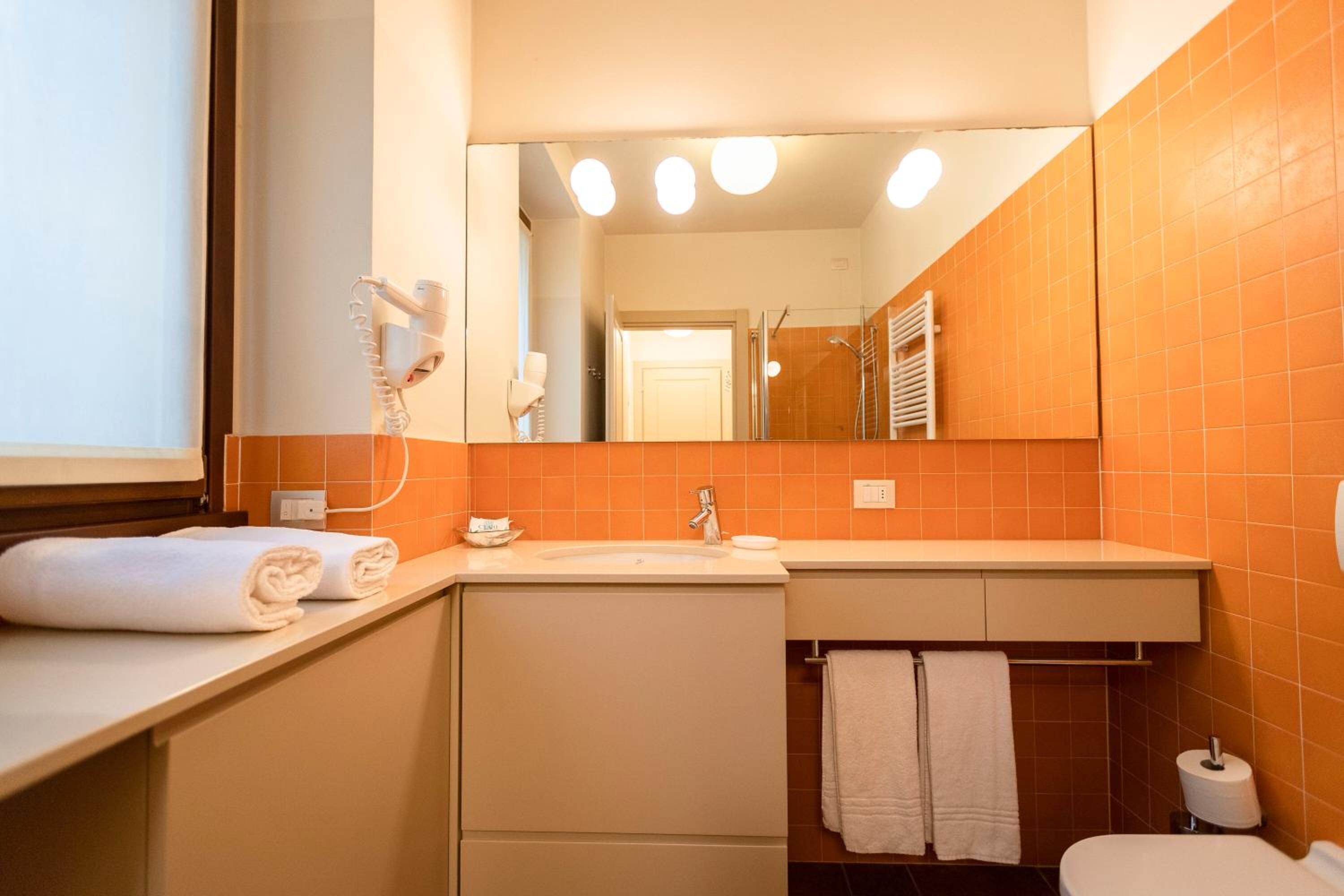 Un baño con lavamanos, espejo y toallero.