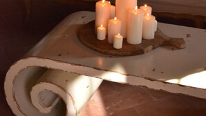 Um quarto aconchegante com um sofá, uma mesa de jantar com velas e uma cadeira de madeira.