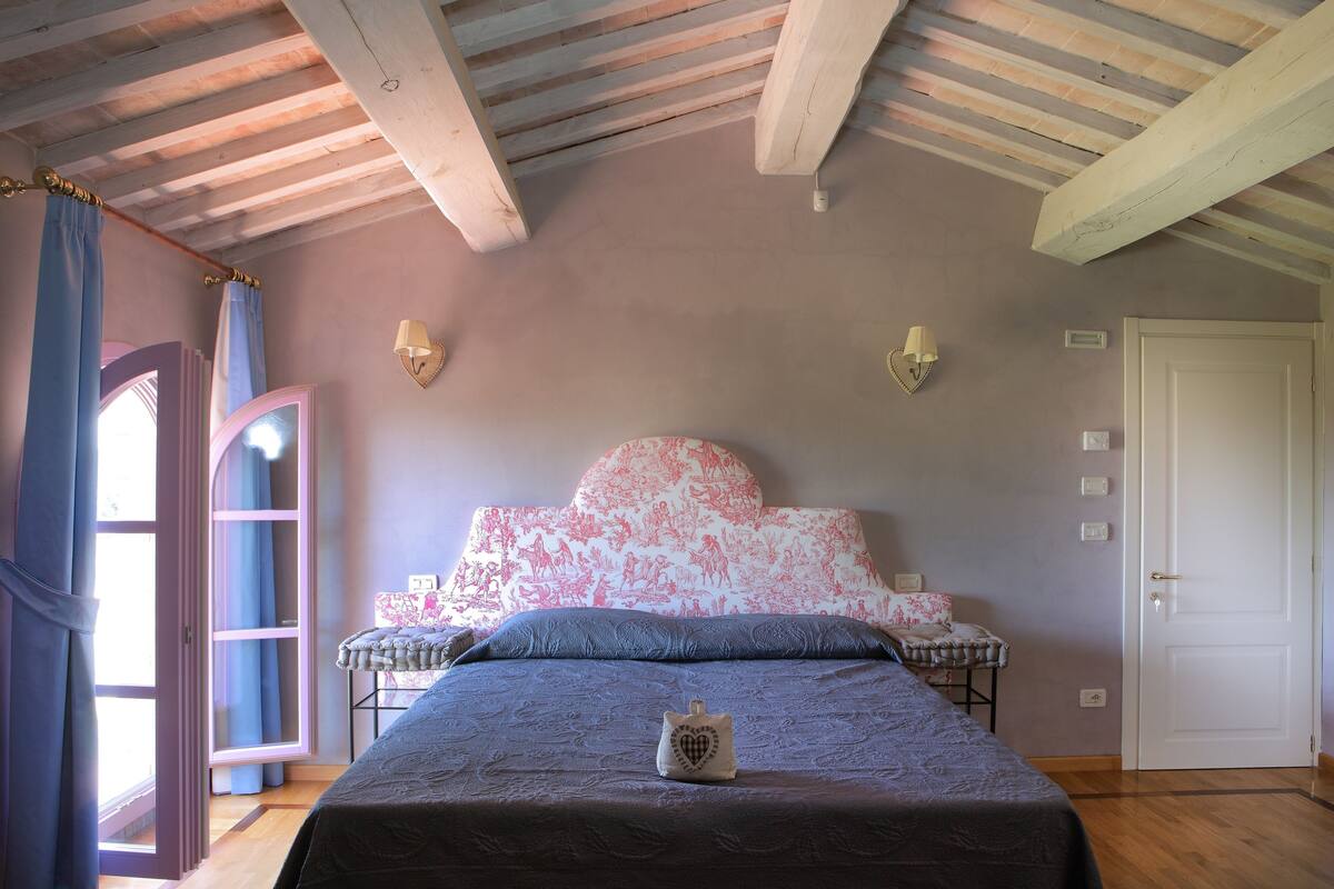 A bedroom with a bed, a nightstand, a door, and a window with curtains.