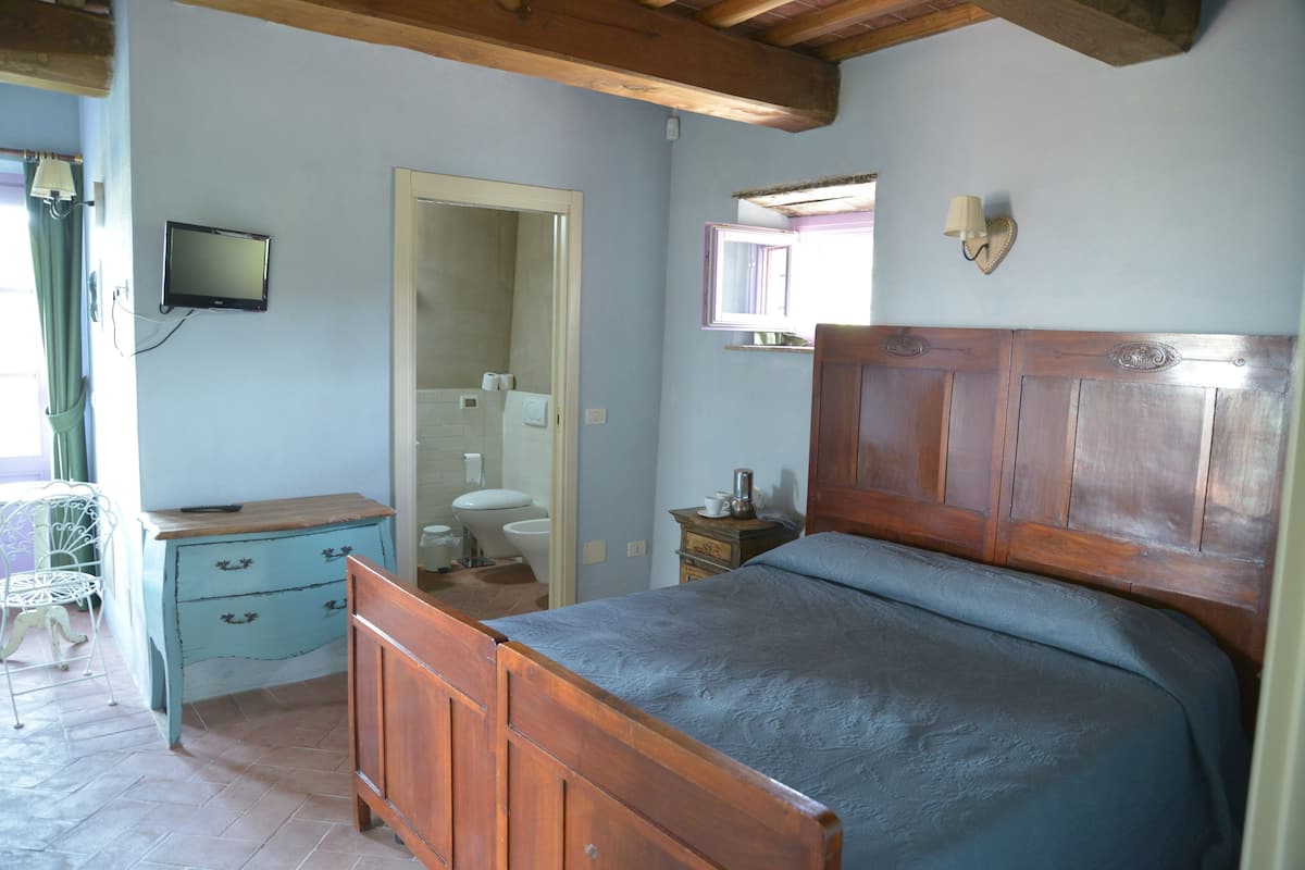 A bedroom with a wooden bed, a dresser, a mirror, and a television on the wall.