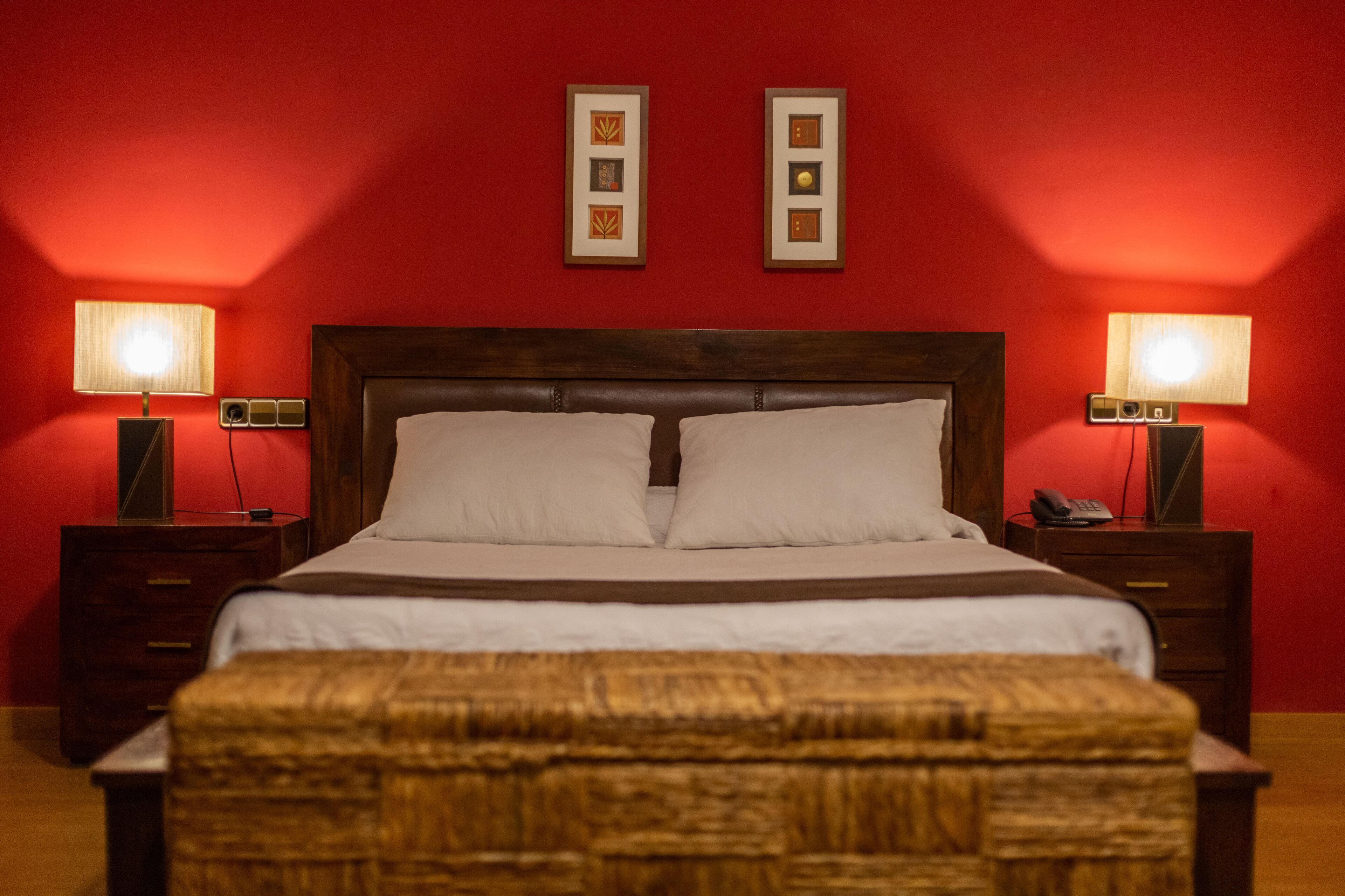 A neatly made bed with two pillows, a wooden headboard, and two bedside tables with lamps.