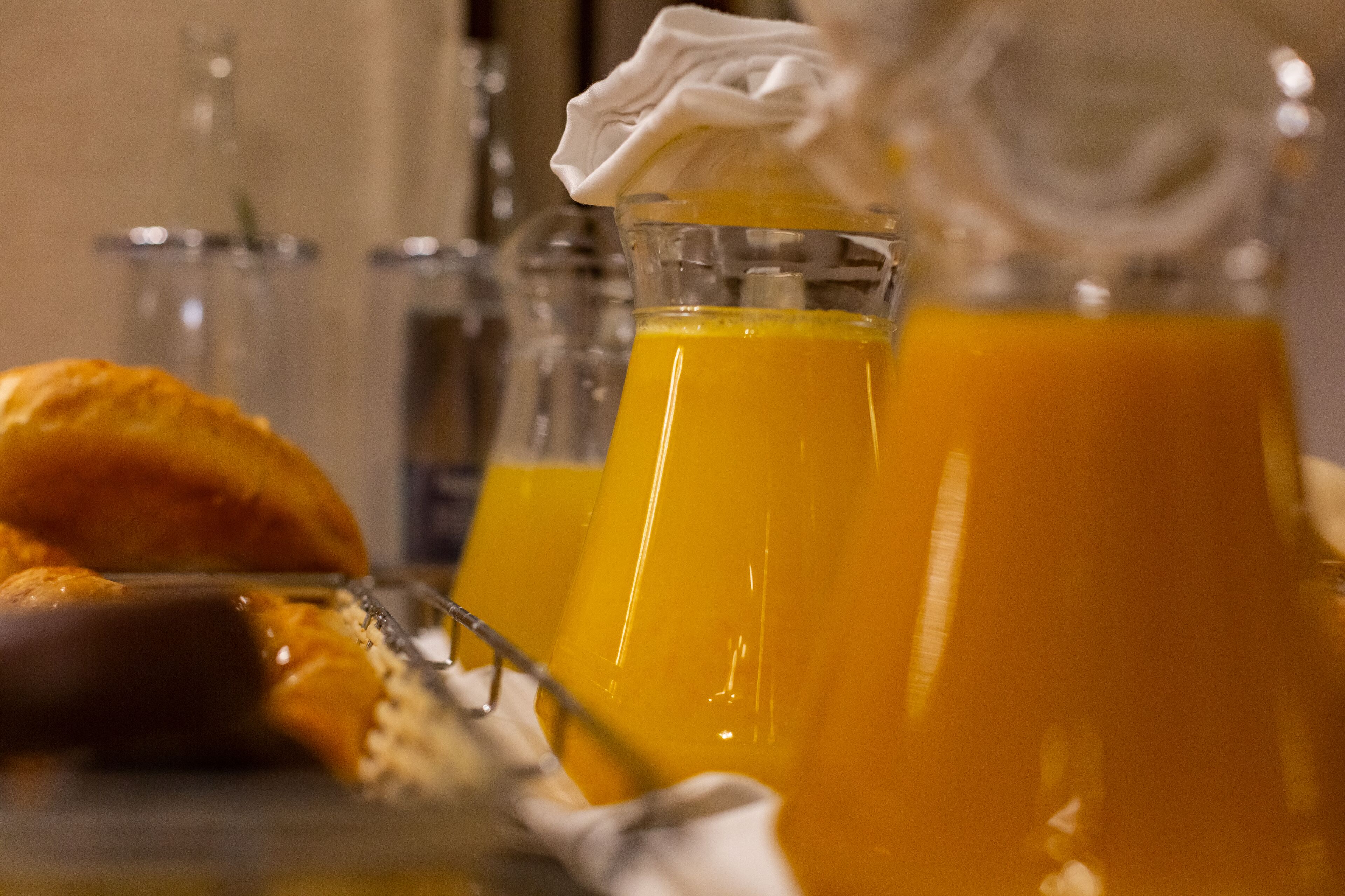 Un desayuno con jugo de naranja, un croissant y un cuchillo sobre un plato.
