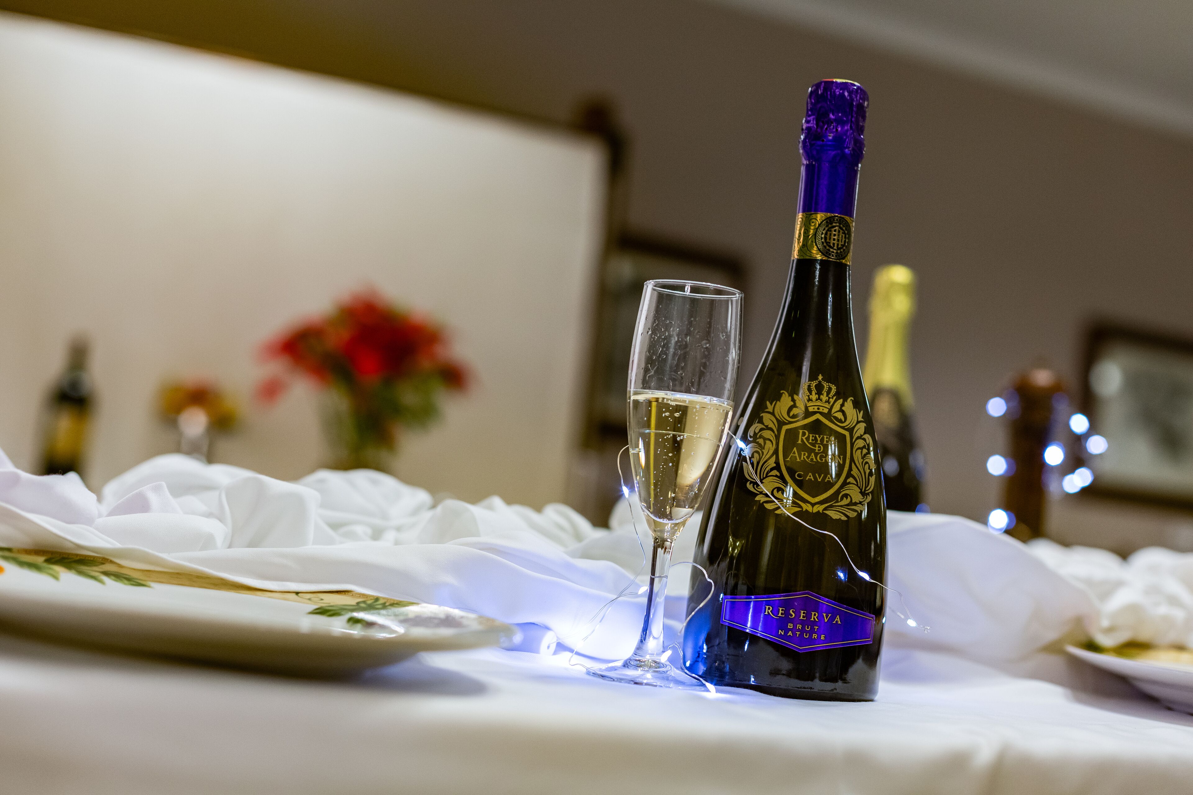 Une bouteille de champagne et un verre posés sur une table recouverte d’une nappe blanche.