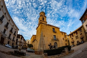 A historic building with a bell tower, surrounded by other buildings and a fountain in the foreground.