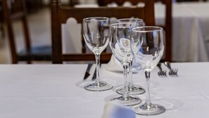 Une table à manger dressée avec des verres à vin et des couverts, avec la salle à manger en arrière-plan.