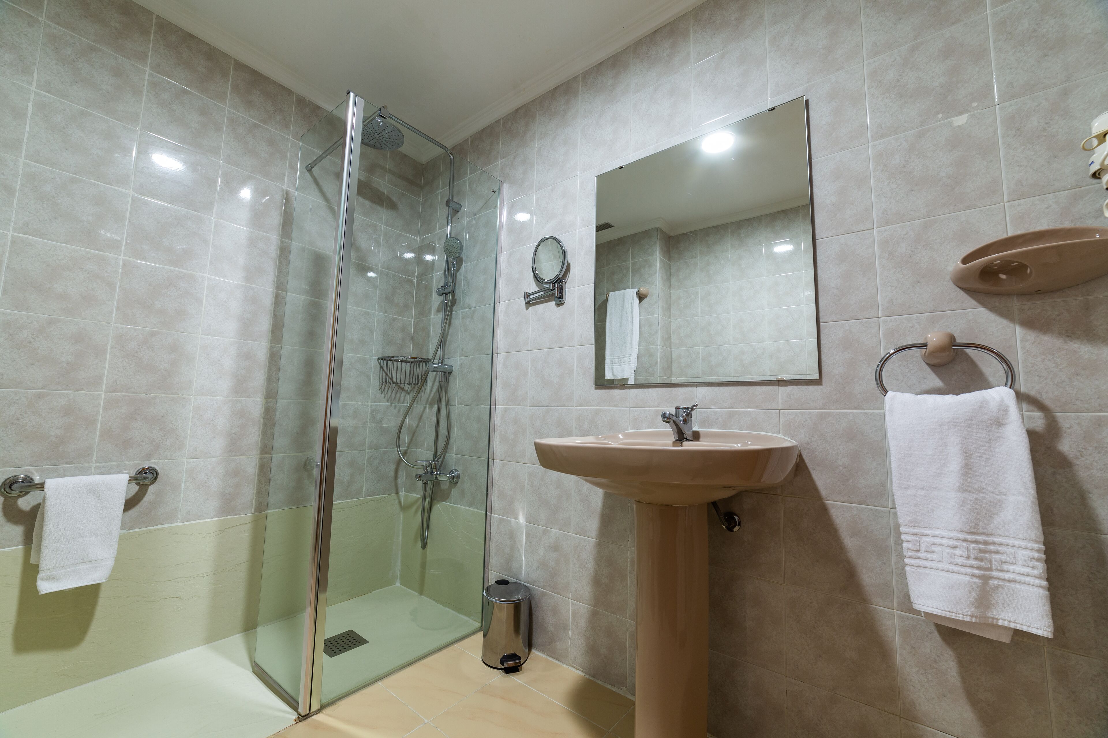 A modern bathroom with a glass shower enclosure, a sink, and a mirror.