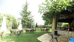 Une terrasse extérieure aménagée avec des meubles en osier, une table en pierre et un coin bar avec un mur en pierre.