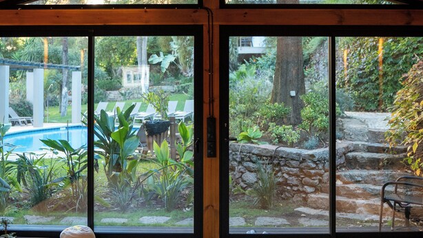 Una habitación amplia con techo alto y ventanas grandes con vistas a un jardín.