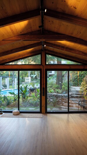 Une pièce spacieuse avec un plafond haut et de grandes fenêtres donnant sur un jardin.