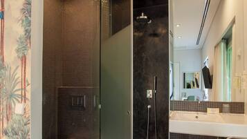 Een moderne badkamer met een douchecabine van glas, een wit wastafelmeubel en een toilet.