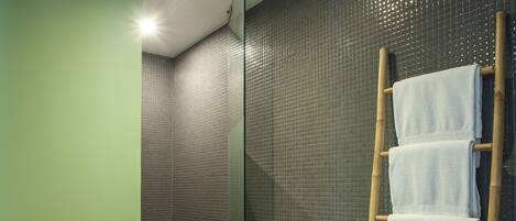 A bathroom with a white sink, a glass shower enclosure, and a bamboo towel rack with towels.