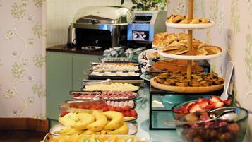 Een buffettafel met diverse soorten eten, waaronder fruit, gebak en belegde broodjes.