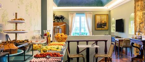 A breakfast buffet with various food items and a dining area with wicker chairs and a table.