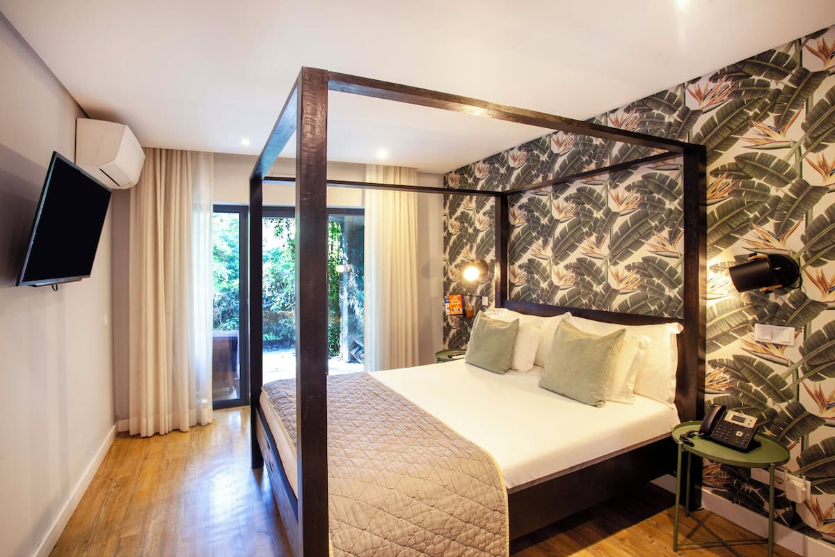 Un dormitorio moderno con una cama grande, un televisor y un teléfono sobre una mesita de noche.
