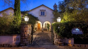 Un edificio histórico con una entrada adoquinada, arcos y un letrero que dice 'CASAVELA'.