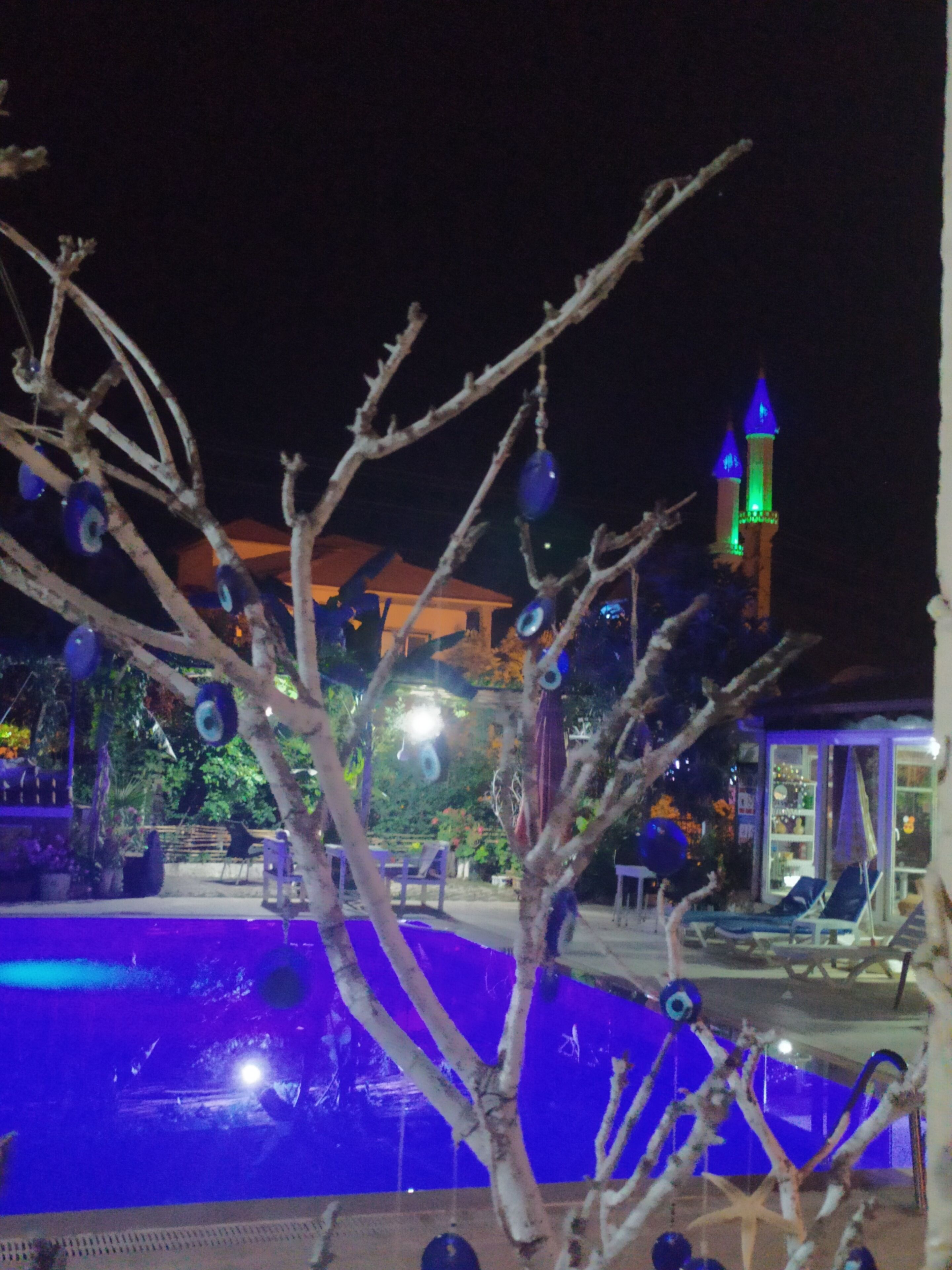 A nighttime view of a pool area with decorative lights and a tower in the background.