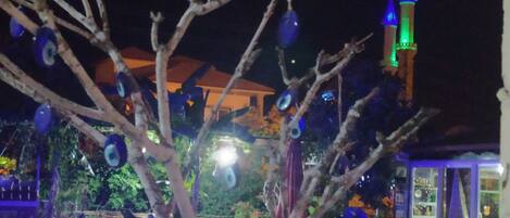 A nighttime view of a pool area with decorative lights and a tower in the background.